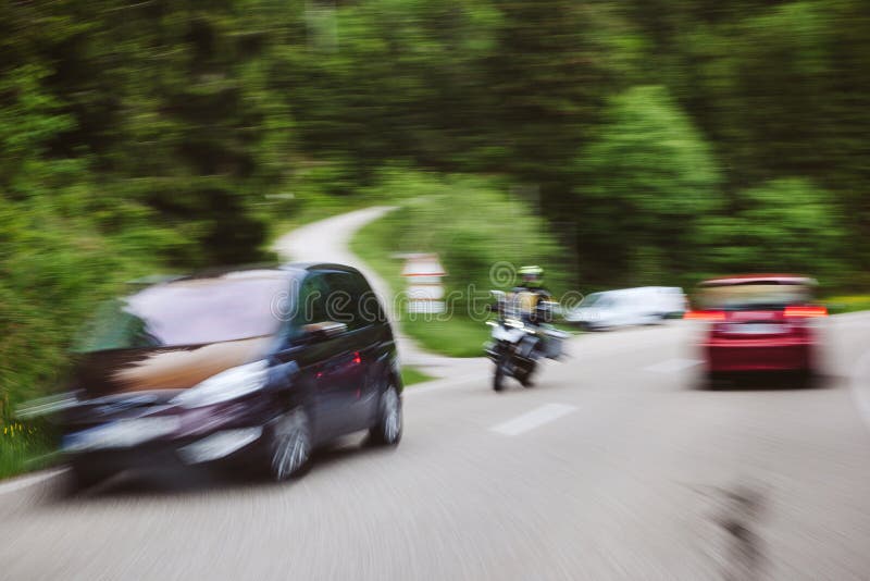 Accident situation with motorcycle and two cars on highway surrounded by tree forest