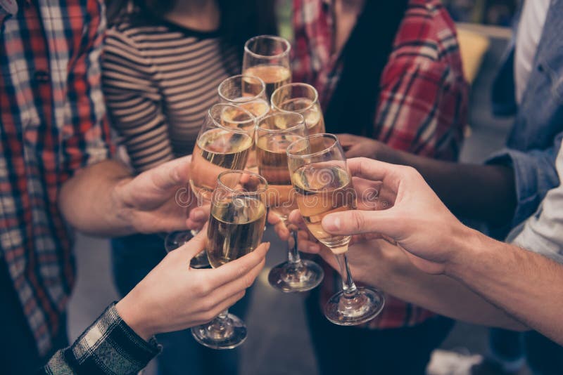 Acclamazioni! Chiuda su dei migliori amici tintinnanti con i bicchieri di vino che si tengono per mano la celebrazione scintillan immagine stock Acclamazioni! Chiuda su dei migliori amici tintinnanti con i bicchieri di vino che si tengono per mano la celebrazione scintillan immagine stock