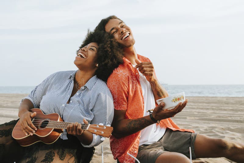 Accoppi avere un picnic alla spiaggia immagine stock Accoppi avere un picnic alla spiaggia immagine stock