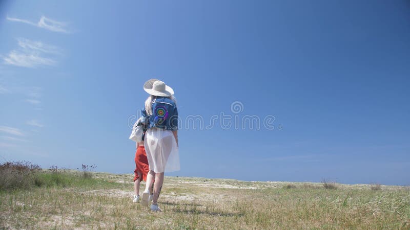 Accoppi delle giovani donne che camminano la spiaggia sabbiosa allo Swimwear indipendente di stile di boho del giorno e mette