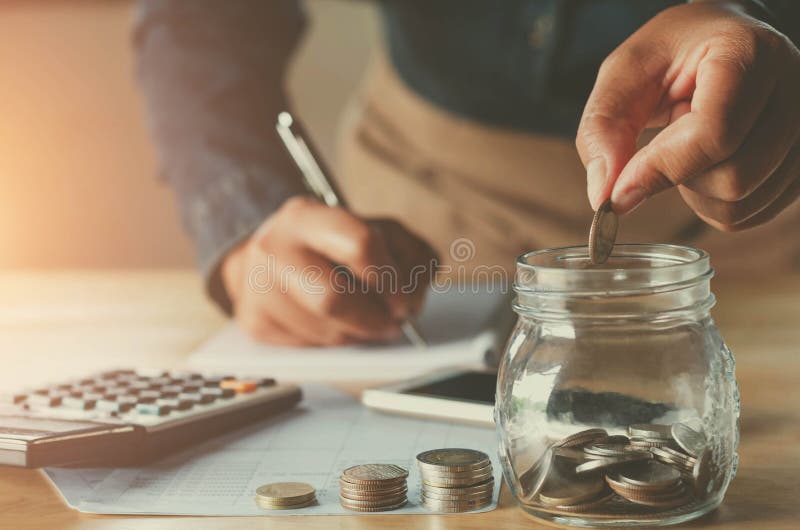 Accountin d'affaires avec l'argent d'économie avec la main mettant des pièces de monnaie dedans images stock