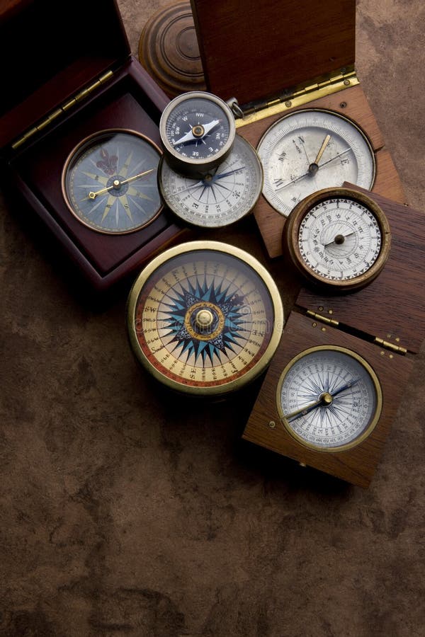 A group of antique compasses on a weathered paper background. A group of antique compasses on a weathered paper background