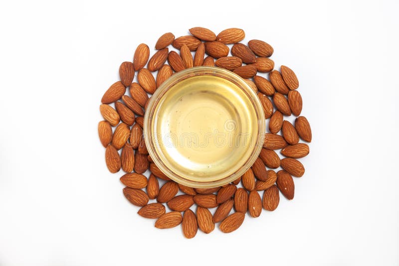 Aceite de almendras dulce en tazón de vidrio primera extracción y nueces de almendras secas como ingrediente para la pastelería acercarse a fondo blanco
