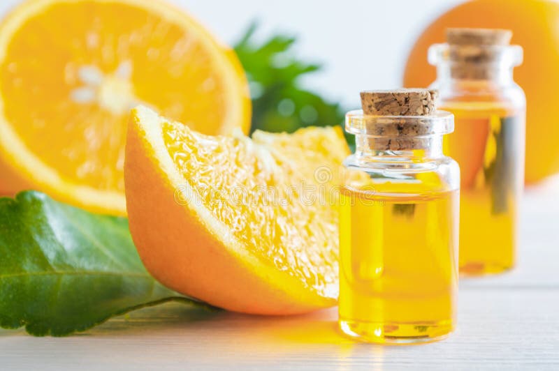 Aceite esencial anaranjado natural en botella y fruta de las naranjas del corte en la tabla de madera blanca foto de archivo libre de regalías Aceite esencial anaranjado natural en botella y fruta de las naranjas del corte en la tabla de madera blanca foto de archivo libre de regalías