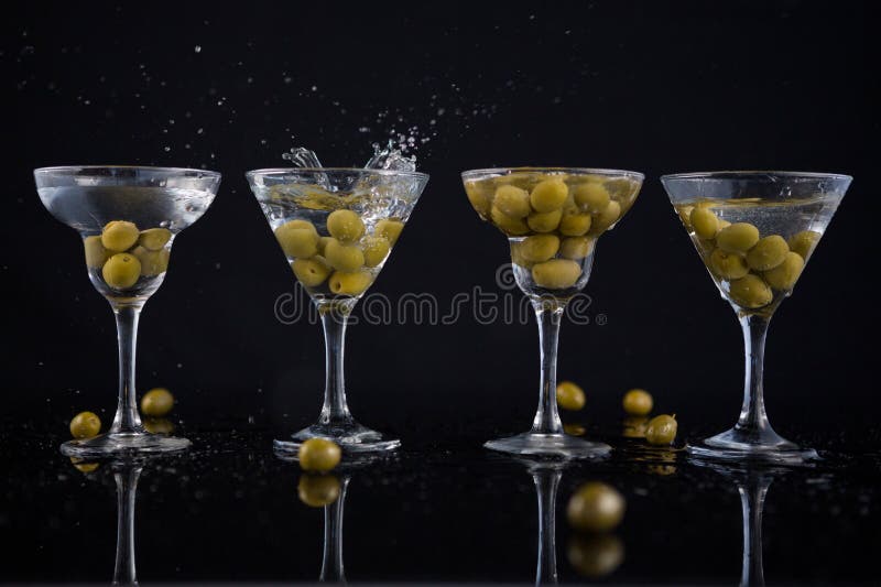 Aceitunas que salpican adentro a un cóctel martini con la cal en la tabla imagenes de archivo Aceitunas que salpican adentro a un cóctel martini con la cal en la tabla imagenes de archivo