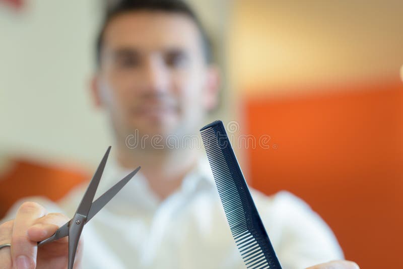 Cabeleireiro secando cabelos loiros à mão com secador de cabelo e escova  redonda em um salão de beleza.