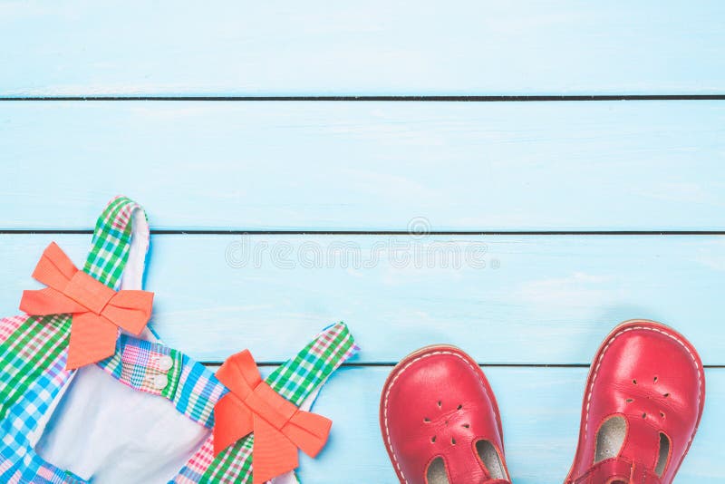 Acessórios da menina Vestido colorido e sapatas vermelhas na luz - fundo pastel de madeira azul Vista superior foto de stock Acessórios da menina Vestido colorido e sapatas vermelhas na luz - fundo pastel de madeira azul Vista superior foto de stock
