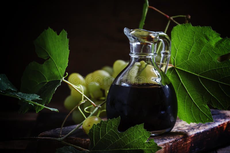 Aceto balsamico in una brocca di vetro, fondo di legno d'annata, ruggine immagini stock Aceto balsamico in una brocca di vetro, fondo di legno d'annata, ruggine immagini stock