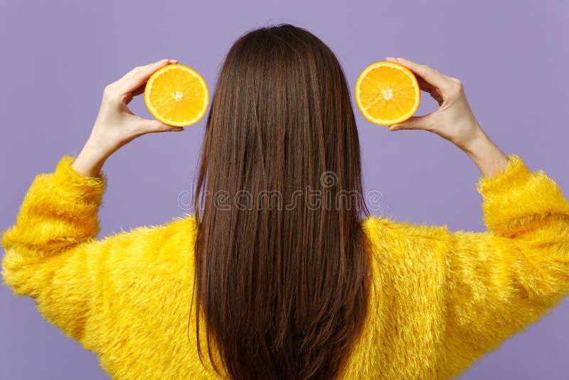 Achter achtermening van jonge vrouw in de holding van de bontsweater halfs van vers rijp oranje die fruit dichtbij haar op vioolt stock foto's Achter achtermening van jonge vrouw in de holding van de bontsweater halfs van vers rijp oranje die fruit dichtbij haar op vioolt stock foto's