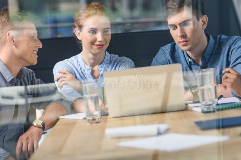 Achter de glasmening van jong team die project in modern bespreken stock afbeelding Achter de glasmening van jong team die project in modern bespreken stock afbeelding
