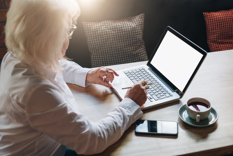 Achter mening Onderneemster teruggetrokken zitting in koffie bij lijst, die aan laptop werken Telework, online onderwijs, e-leert stock afbeelding Achter mening Onderneemster teruggetrokken zitting in koffie bij lijst, die aan laptop werken Telework, online onderwijs, e-leert stock afbeelding