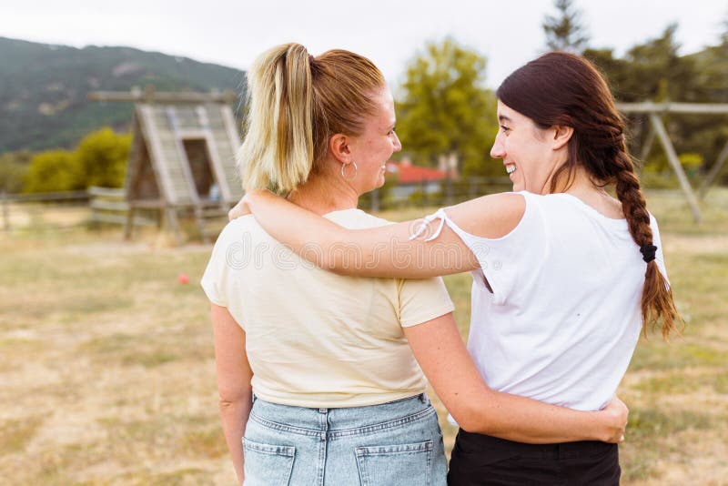 Achteraanzicht van twee vrienden die lachen en elkaar knuffelen op het platteland Beste vriendschapsliefde en vriendschapsconcept stock foto Achteraanzicht van twee vrienden die lachen en elkaar knuffelen op het platteland Beste vriendschapsliefde en vriendschapsconcept stock foto