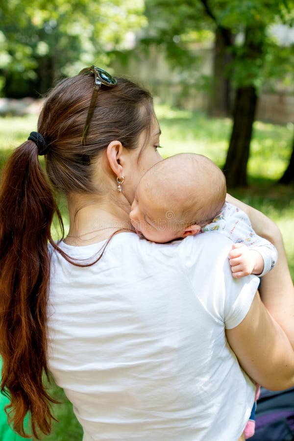 Achtermening die van het houden van van gelukkige moeder gevende leuke baby, de baby geven die aan oprisping na maaltijd, baby he royalty-vrije stock foto Achtermening die van het houden van van gelukkige moeder gevende leuke baby, de baby geven die aan oprisping na maaltijd, baby he royalty-vrije stock foto