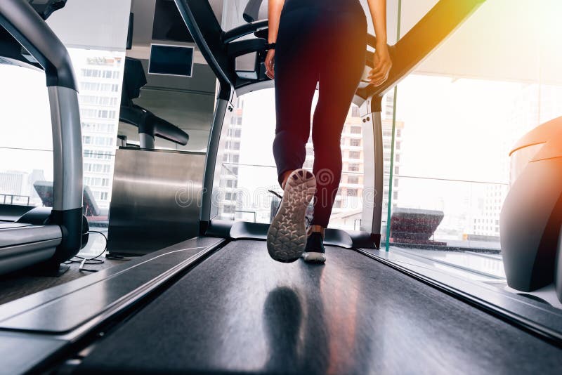 Achtermening van voeten met tennisschoenen van vrouwelijke agent/jogger het lopen op tredmolen binnen in actie stock afbeelding Achtermening van voeten met tennisschoenen van vrouwelijke agent/jogger het lopen op tredmolen binnen in actie stock afbeelding