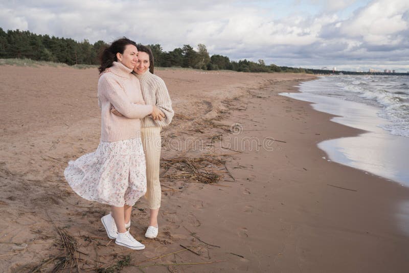 Acogedor paseo de otoño de dos niñas a orillas del mar ventoso. hermanas adultas están buscando mantas del viento. a imágenes de archivo libres de regalías