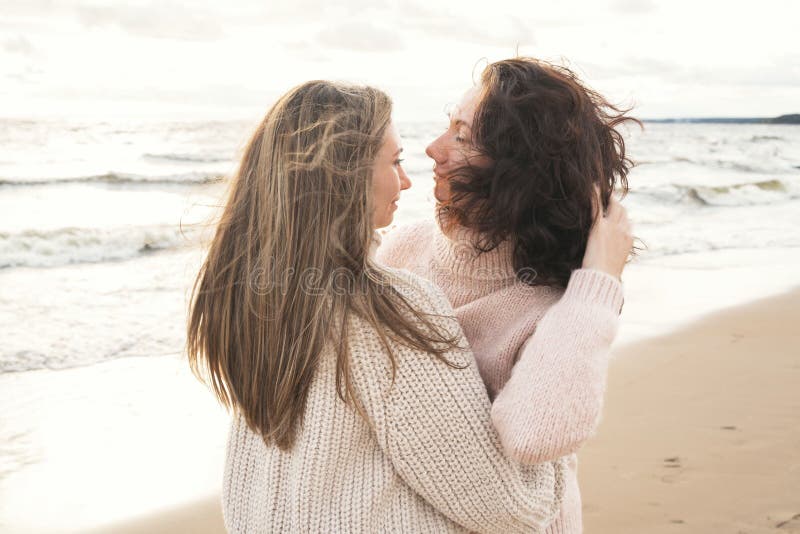 Acogedor paseo de otoño de dos niñas a orillas del mar ventoso. hermanas adultas están buscando mantas del viento. a foto de archivo