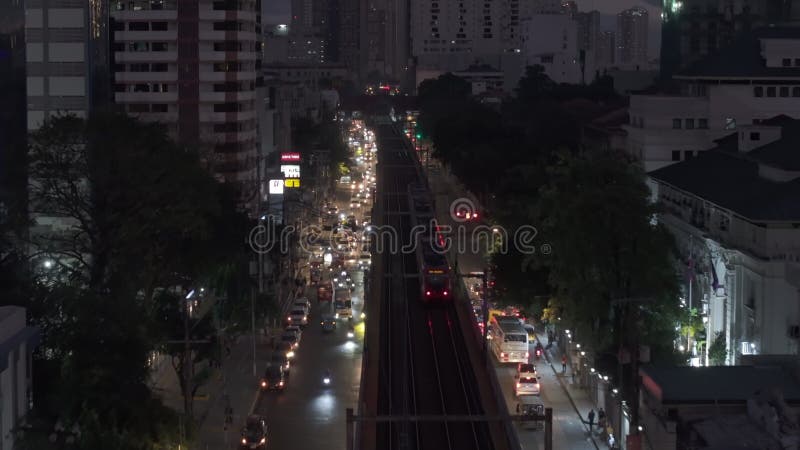 Acompanhamento do comboio de passageiros à noite no bairro urbano. estradas multifaixas e edifícios altos na cidade. manila