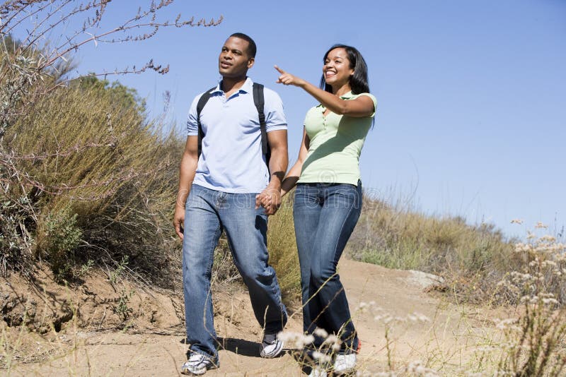 Acople o passeio nas mãos da terra arrendada do trajeto e o sorriso imagens de stock Acople o passeio nas mãos da terra arrendada do trajeto e o sorriso imagens de stock