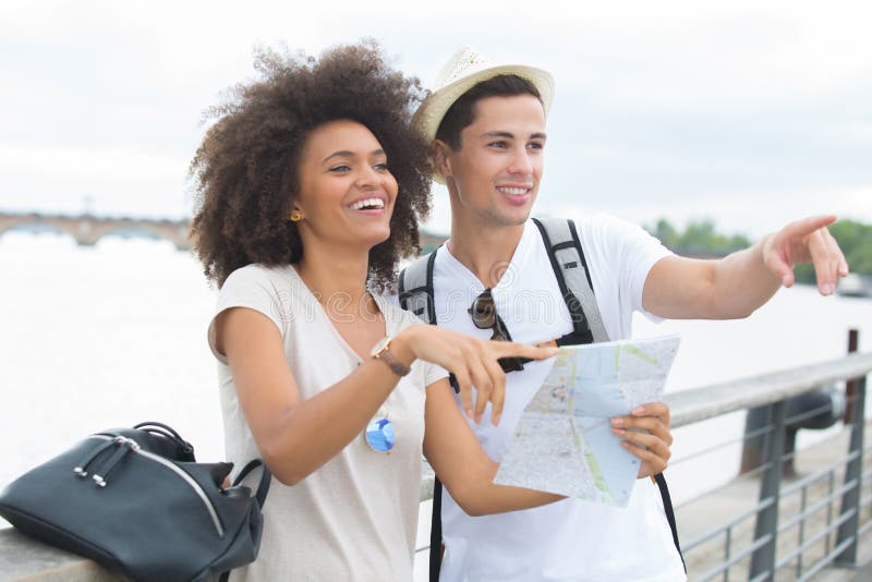 Acople turistas com o mapa perto do rio na cidade foto de stock Acople turistas com o mapa perto do rio na cidade foto de stock