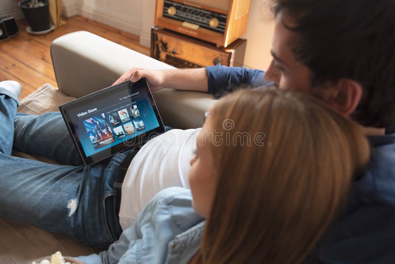 Acople usando a tabuleta digital para o filme de observação no serviço de VOD fotografia de stock Acople usando a tabuleta digital para o filme de observação no serviço de VOD fotografia de stock
