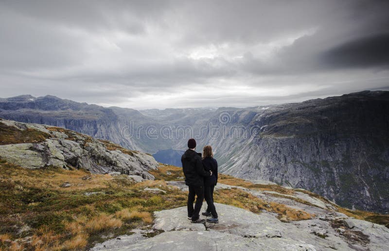 Acople a viagem, os pares de A olhando a grande vista de montanhas e de geleiras da neve em Noruega imagens de stock royalty free Acople a viagem, os pares de A olhando a grande vista de montanhas e de geleiras da neve em Noruega imagens de stock royalty free