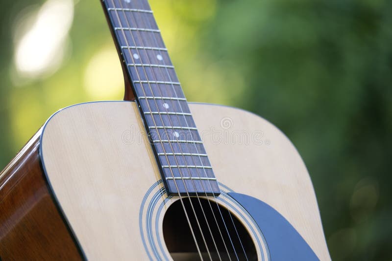Acoustic Guitar Outdoors on Greenery Background. Concept of Calm Music
