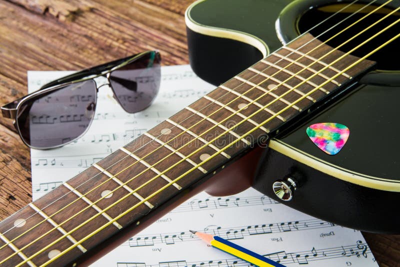 Acoustic Guitar, Sunglasses and Sheet Musical Notes on the Table Stock