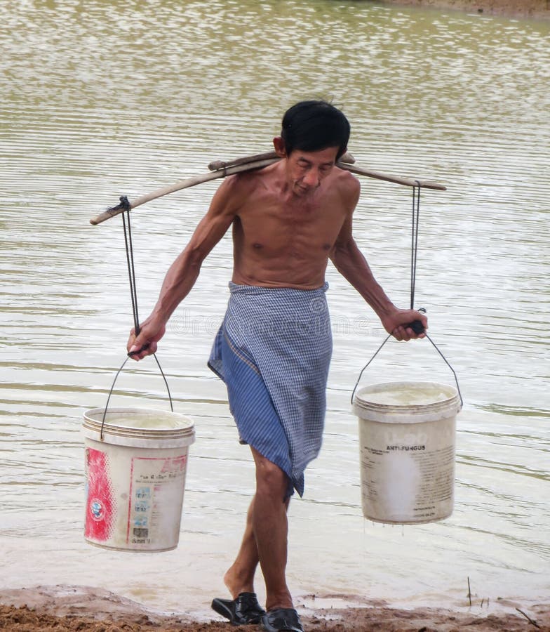 Acqua di trasporto dell'uomo cambogiano anziano immagini stock Acqua di trasporto dell'uomo cambogiano anziano immagini stock