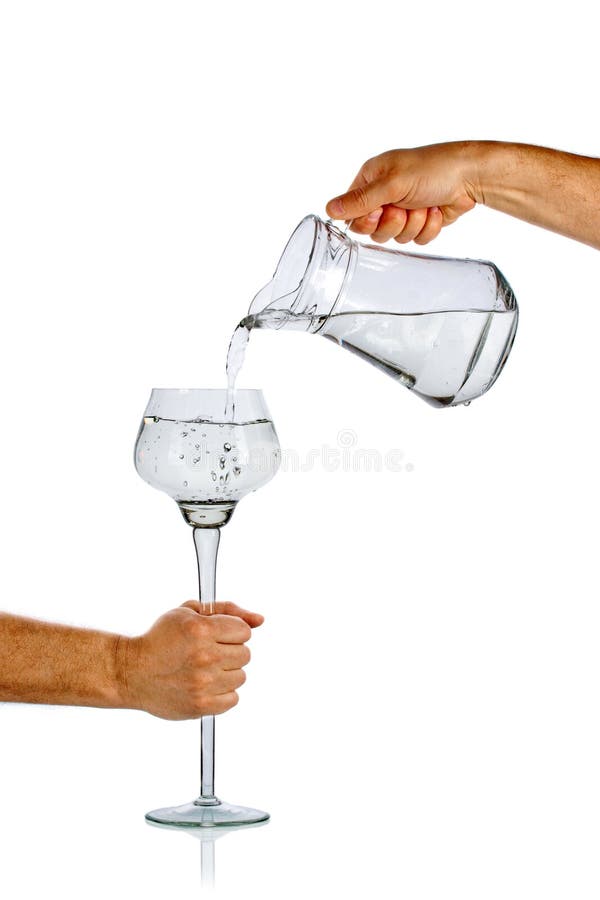 Acqua di versamento della mano dalla brocca di vetro