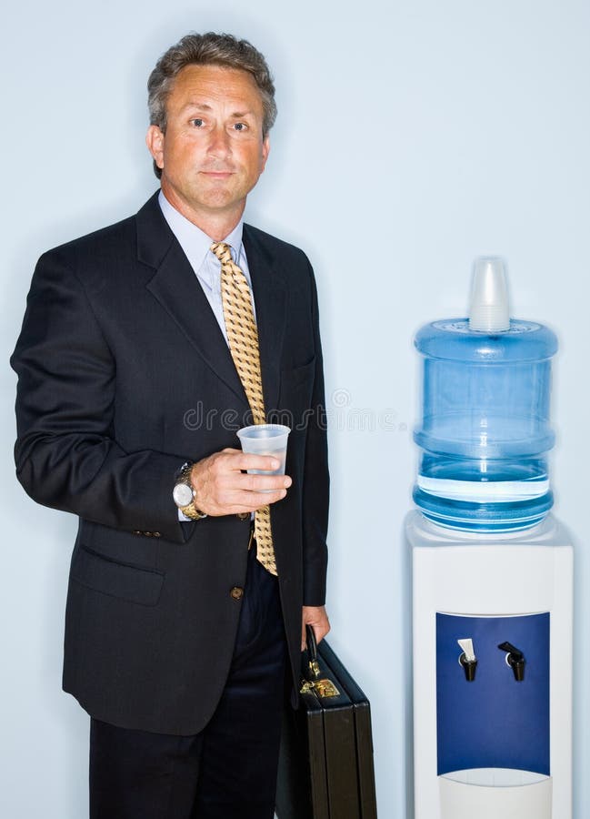 Acqua potabile dell'uomo d'affari dal dispositivo di raffreddamento di acqua immagine stock