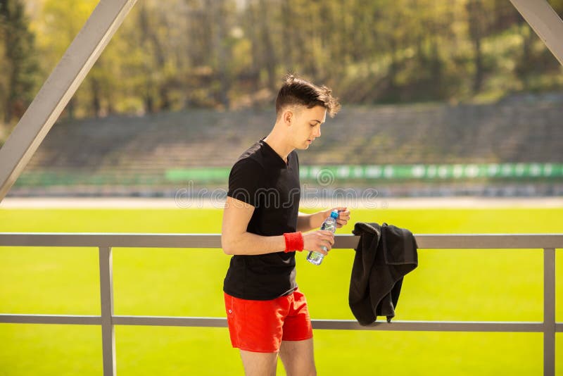Acqua potabile dell'uomo di forma fisica dalla bottiglia Atleta assetato che ha bevanda fredda del rinfresco dopo l'esercizio int fotografie stock libere da diritti Acqua potabile dell'uomo di forma fisica dalla bottiglia Atleta assetato che ha bevanda fredda del rinfresco dopo l'esercizio int fotografie stock libere da diritti