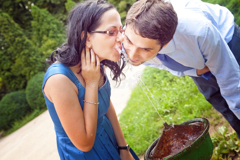 Acqua potabile delle coppie romantiche dalla fontana della sosta fotografia stock