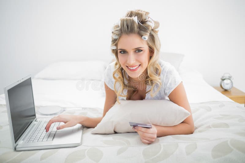 Acquisto biondo sveglio sorridente online facendo uso del computer portatile immagini stock libere da diritti Acquisto biondo sveglio sorridente online facendo uso del computer portatile immagini stock libere da diritti