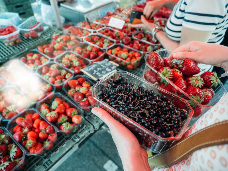 Acquisto della donna per il mercato fresco delle fragole e del ribes fotografie stock