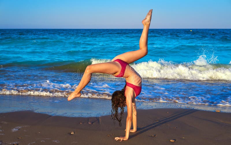 Acrobatic gymnastics bikini girl in a beach. 