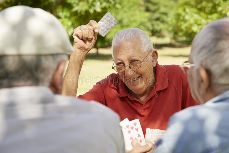 Actieve oudsten, groep oude vriendenspeelkaarten bij park