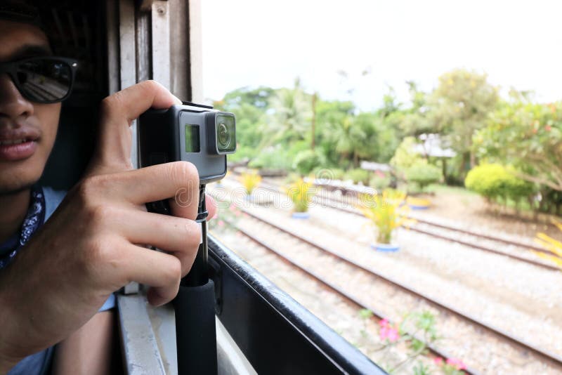 Action camera taking a picture of nature landscape through windows of the train by hands of tourist.