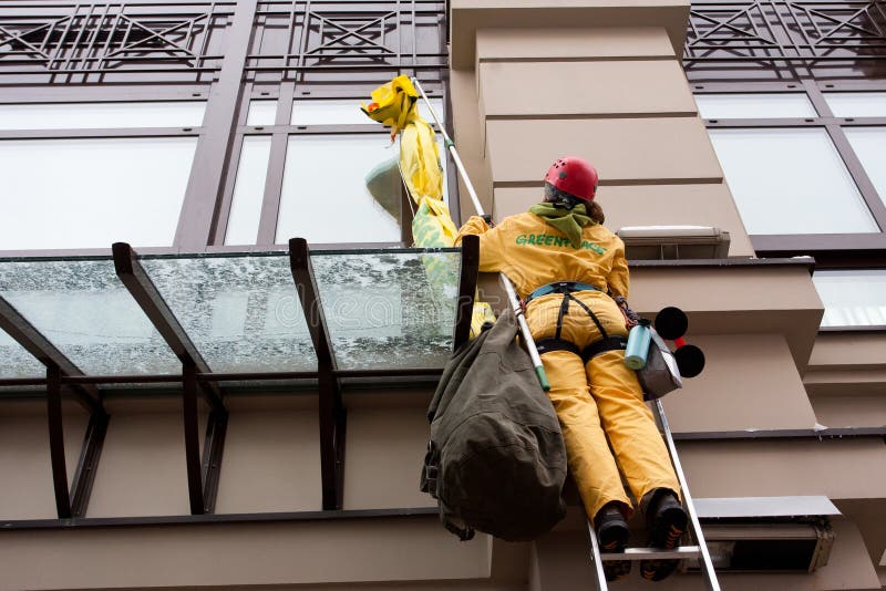 Greenpeace activists in radiation protection suits urges bank EBRD not to loan to Ukraine for building new nuclear reactors in Rivne & Khmelnytsky on 7 January 2012 in Kiev, Ukraine. Female climbing high risk building stock images, royalty-free photos and pictures