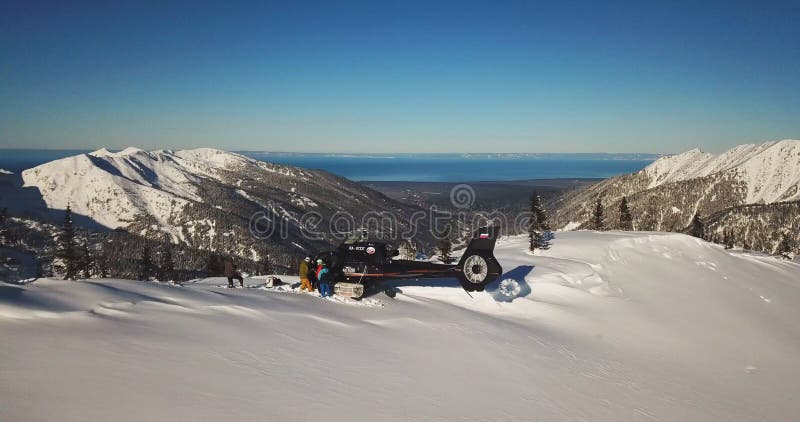 Actionsportler wurden von einem Helikopter an der Bergspitze fallen gelassen Die Sonne scheint hell am blauen Himmel