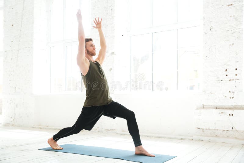 Actitud parctising concentrada de la yoga del hombre joven en una estera de la aptitud