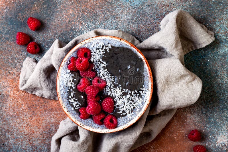 Activated charcoal smoothie and chia seed pudding bowl, vegan detox dessert with raspberry and coconut milk. Overhead, top view royalty free stock images