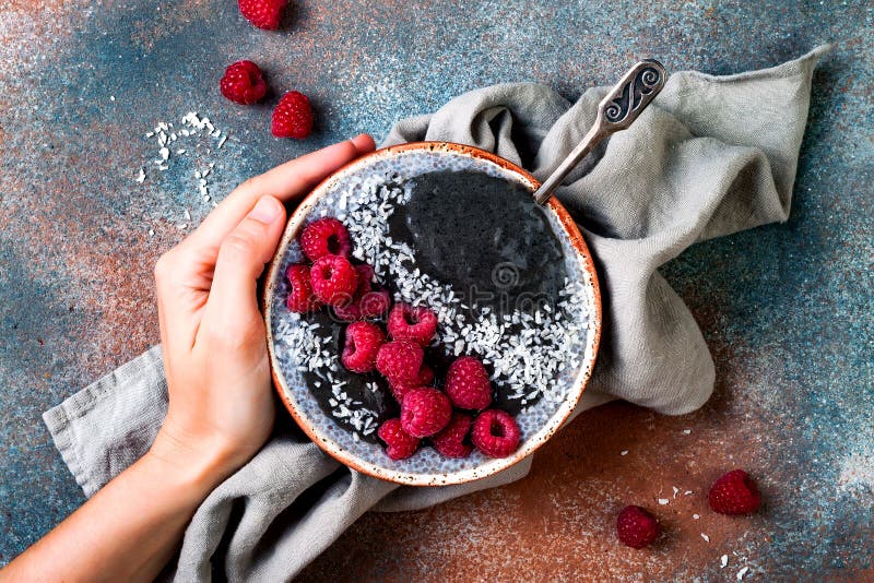 Activated charcoal smoothie and chia seed pudding bowl, vegan detox dessert with raspberry and coconut milk. Overhead, top view stock photography