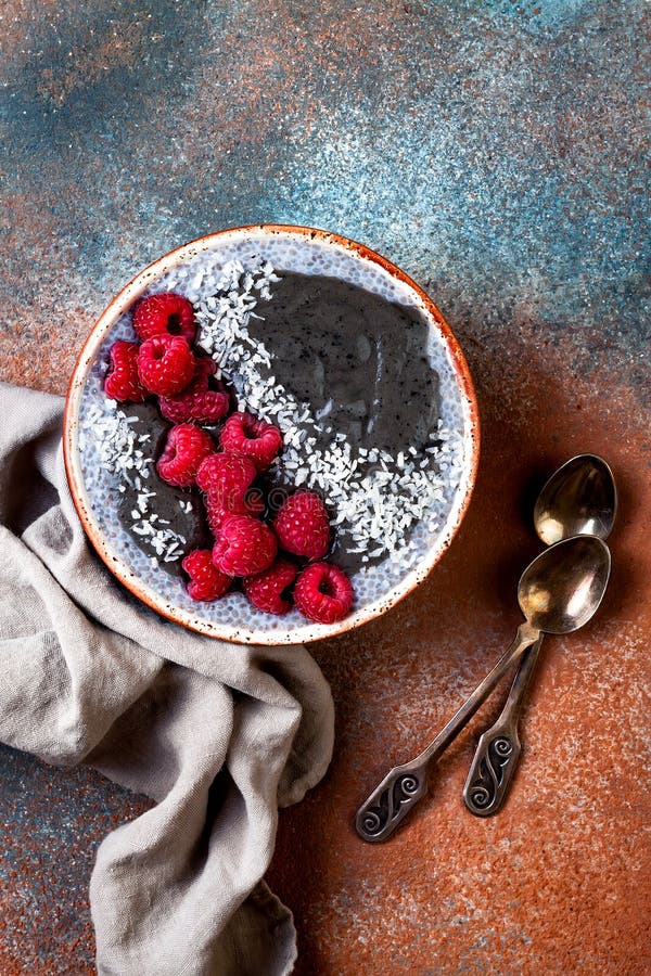 Activated charcoal smoothie and chia seed pudding bowl, vegan detox dessert with raspberry and coconut milk. Overhead, top view stock photo