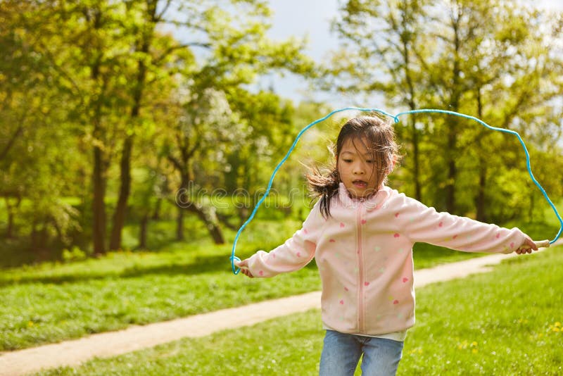 Active child jumps with the skipping rope in the park in the summer during the holidays