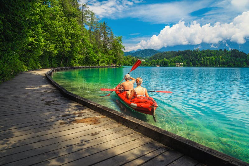Active couple canoeing and enjoying the view, lake Bled, Slovenia. Active sporty couple rowing in the inflatable boat and enjoying the view, lake Bled, Slovenia