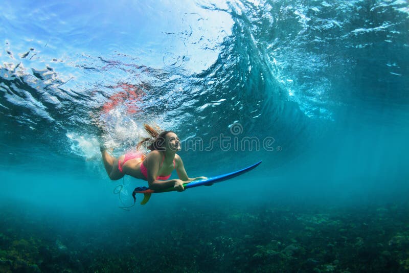 Active girl in bikini in dive action on surf board