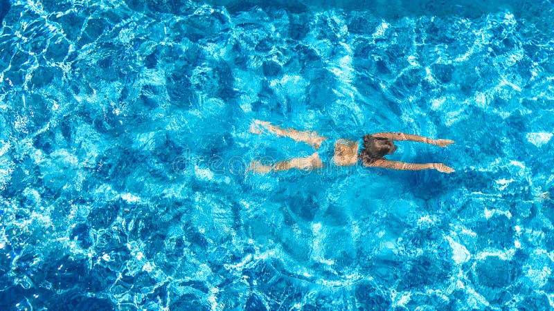 Active girl in swimming pool aerial drone view from above, young woman swims in blue water, tropical vacation, holiday on resort