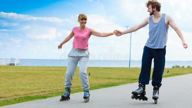 Young couple holding hands while rollerblading royalty free stock photos Young couple holding hands while rollerblading royalty free stock photos
