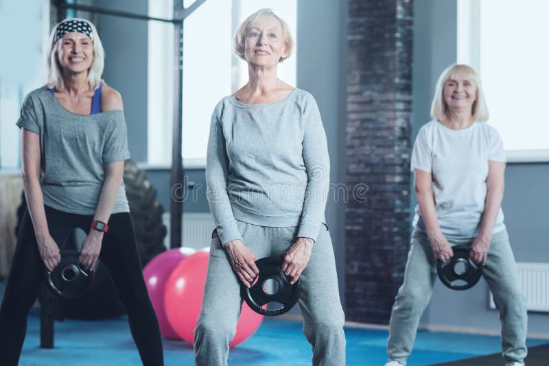 Active mature women swinging weight disk at gym royalty free stock images Active mature women swinging weight disk at gym royalty free stock images