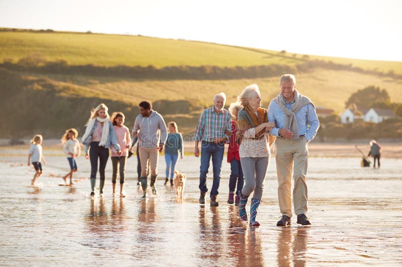 Active Multi-Generation Family With Dog Walking Along Shore On Winter Beach Vacation royalty free stock image